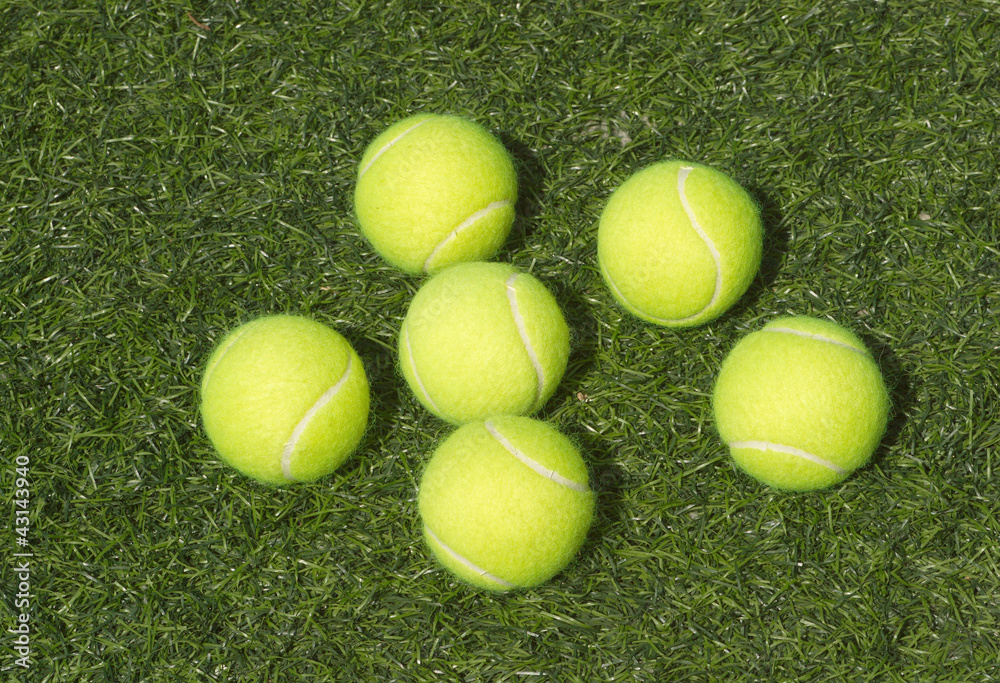 SIx yellow tennis balls lays on green synthetic court grass
