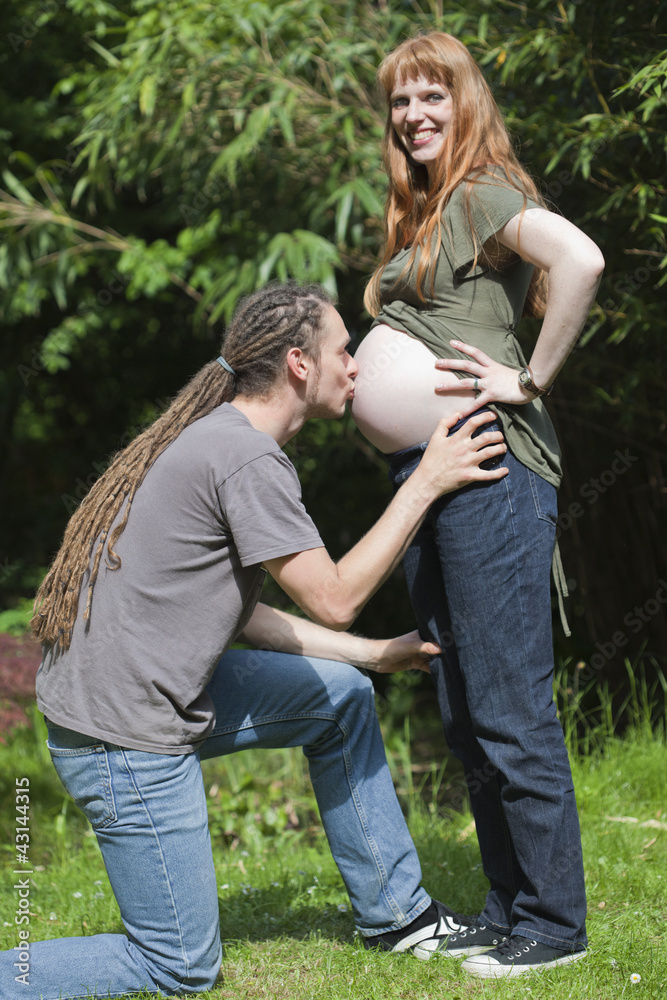 Fototapeta premium Young Man kissing his pregnant wife’s Belly
