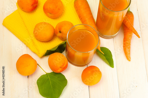 glasses of carrot and  apricot juice on white wooden table