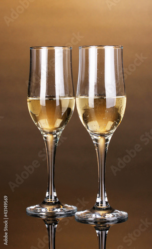 Glasses of champagne on brown background