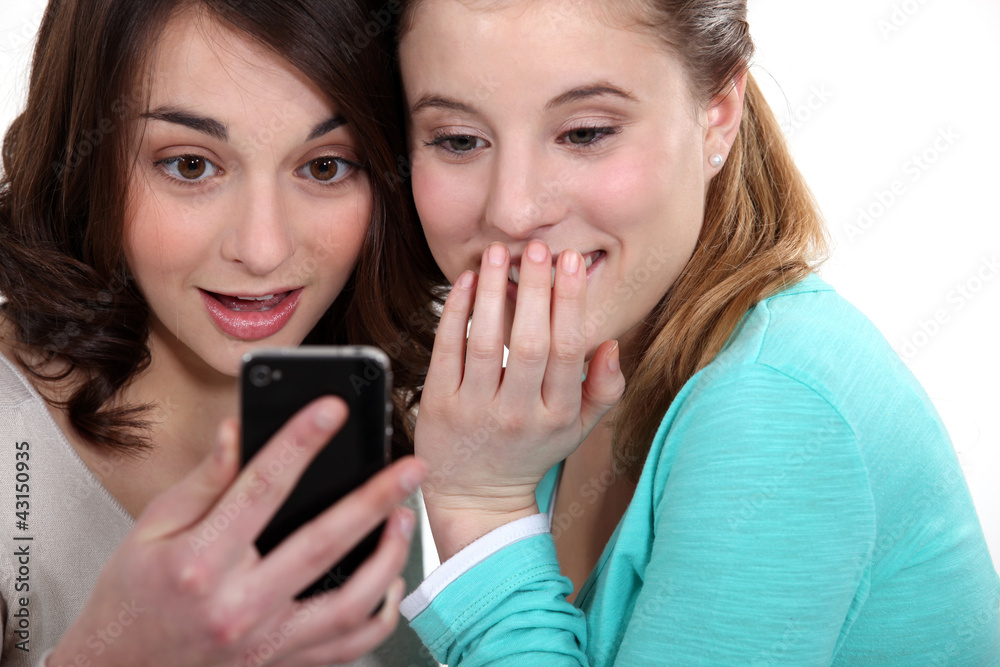 two girlfriends looking at a cell and laughing two girlfriends looking at a cell and laughing