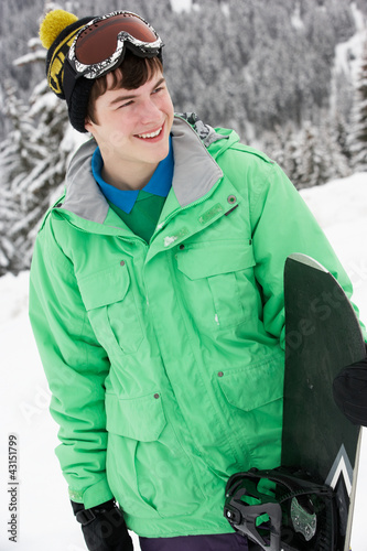 Teenage Boy With Snowboard On Ski Holiday In Mountains