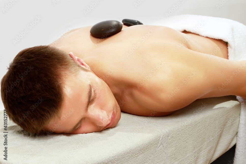 Young man enjoying hot stone treatment
