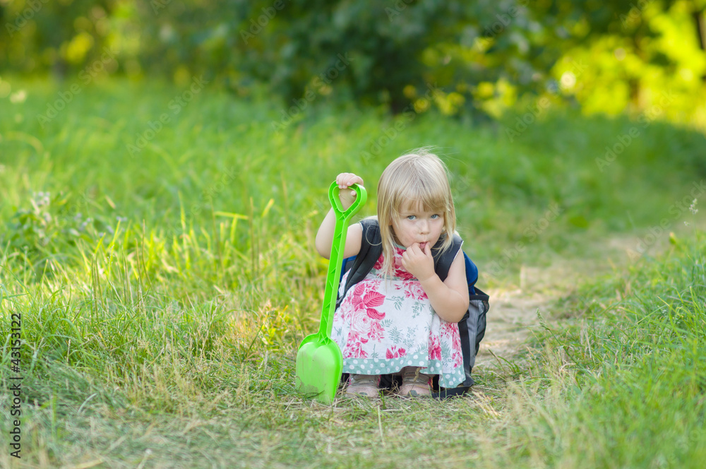 Adorable girl with huge backpack and toy shovel walking in park Adorable girl with huge backpack and toy shovel walking in park