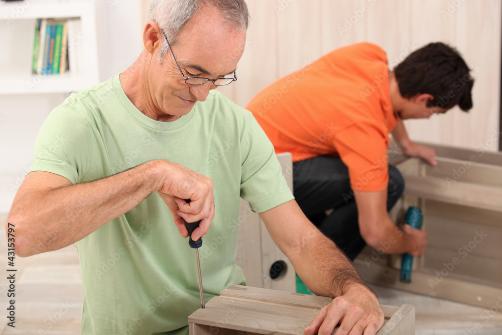 Father and son putting together flatpack furniture Father and son putting together flatpack furniture