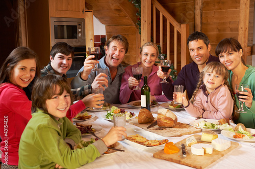 Two Familes Enjoying Meal In Alpine Chalet Together