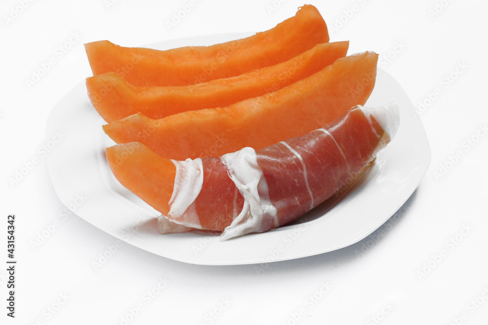 fette di melone con prosciutto su piatto_sfondo bianco fette di melone con prosciutto su piatto_sfondo bianco