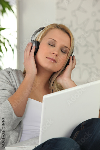 Blond woman listening to music through laptop