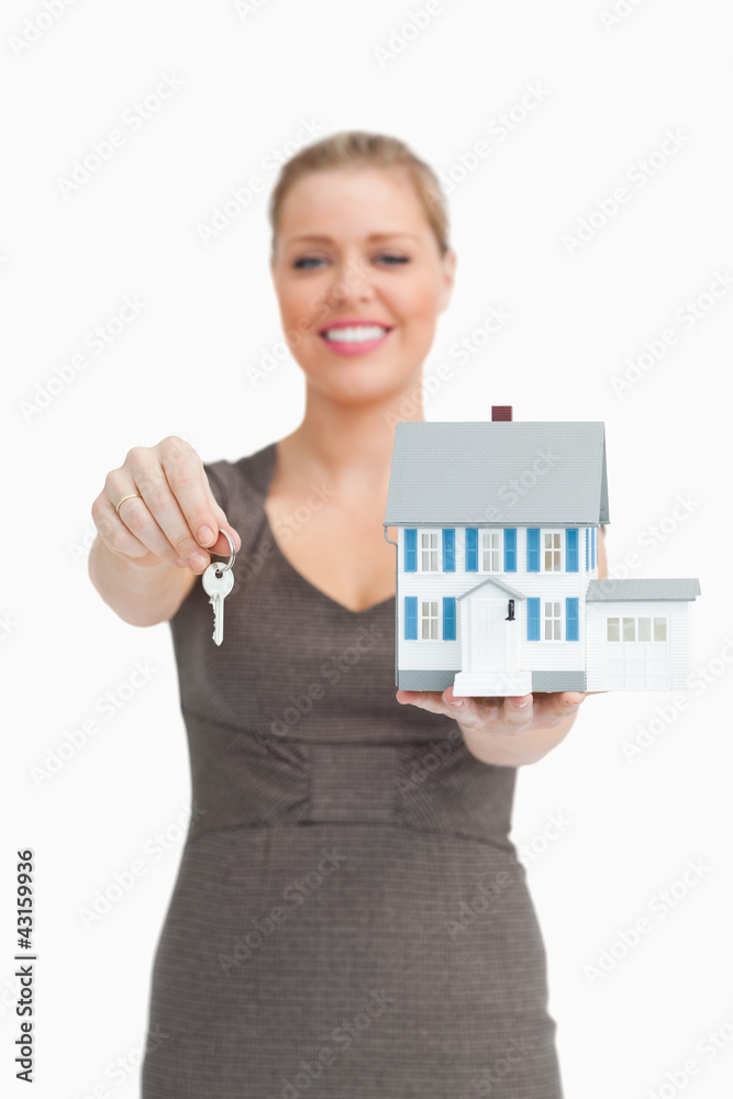 Woman showing a key and a model house Woman showing a key and a model house