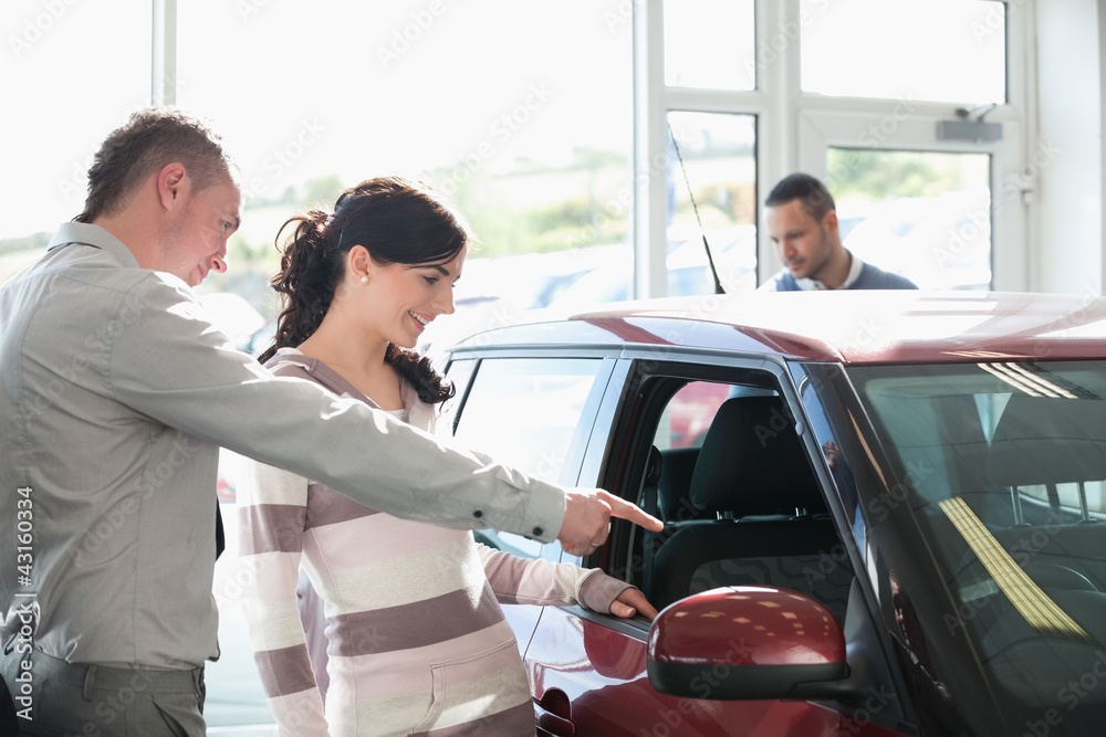 Car dealer pointing the interior of a car with a woman Car dealer pointing the interior of a car with a woman