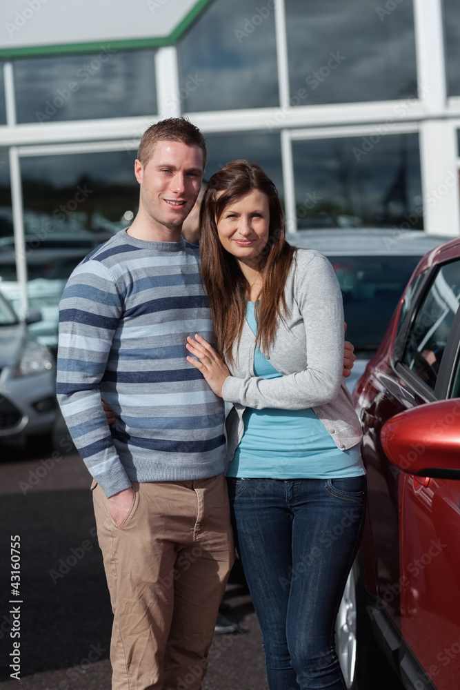 Couple holding tight while standing next to a car
