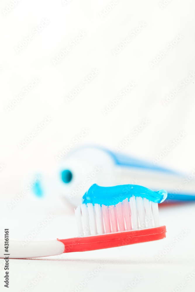 Red toothbrush next to a tube of toothpaste Red toothbrush next to a tube of toothpaste