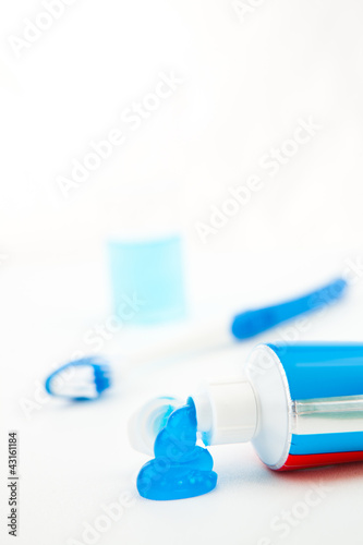 Blue toothbrush next to a tube of toothpaste