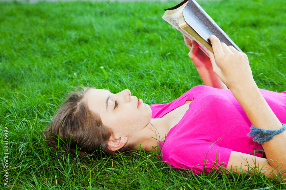 Teen girl reading the Bible outdoors