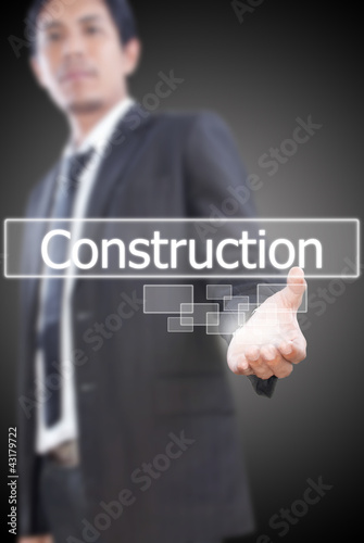 Businessman holding Construction word on the whiteboard.