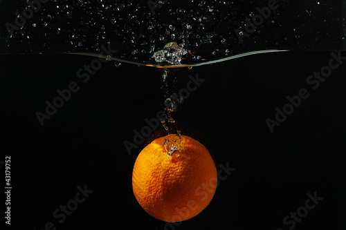 Ripe orange falling into the water with a splash