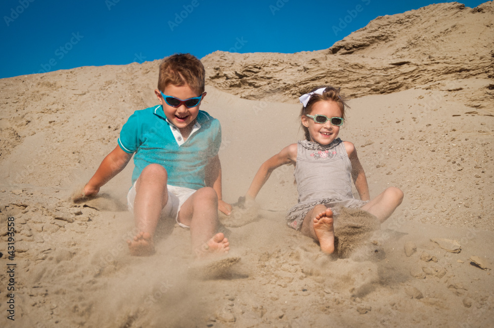Adorable little girl and boy playing on the sandy beach Adorable little girl and boy playing on the sandy beach