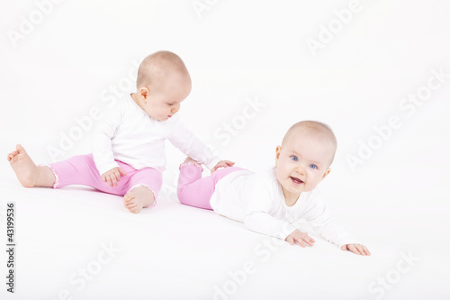 happy identical twin sisters playing on the ground