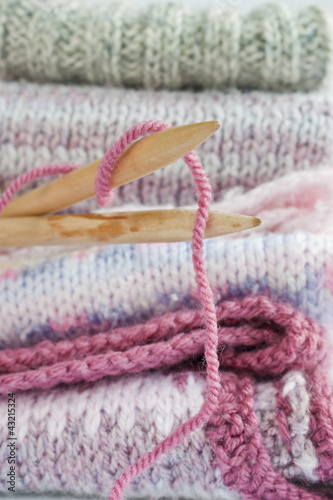 Konstfotografi Knitting needles, knitted warm woollen jumpers and vests.