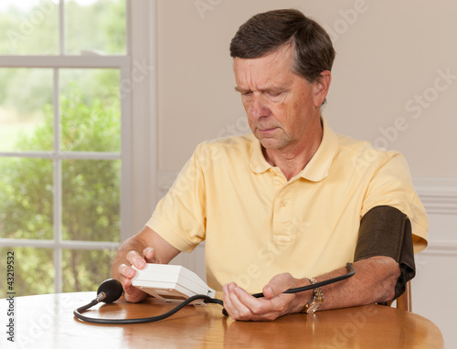Senior man taking blood pressure at home