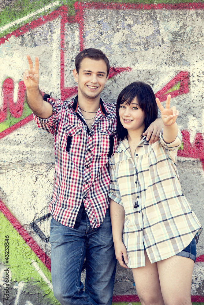 Style teen couple near graffiti background.