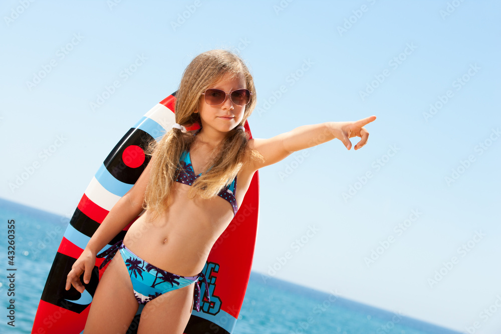Cute girl in bikini pointing with finger outdoors. Photos | Adobe Stock