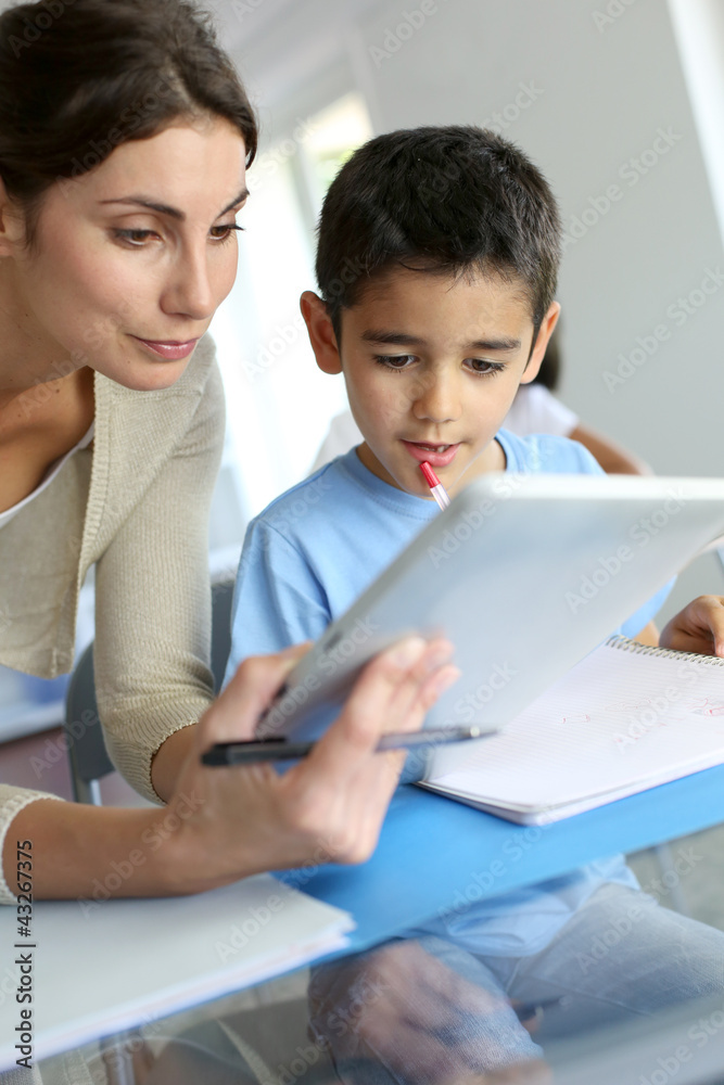Teacher and schoolboy using electronic tablet in class Teacher and schoolboy using electronic tablet in class