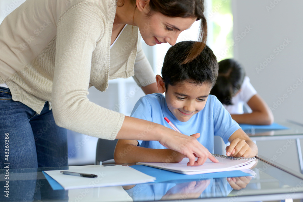 Teacher helping young boy with writing lesson Teacher helping young boy with writing lesson