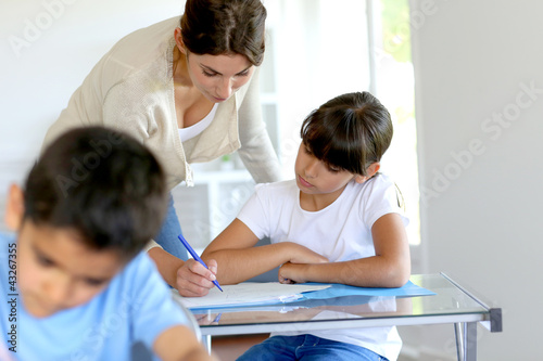 Teacher helping young girl in class with lesson
