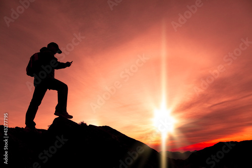 young man using smart phone on the top of mountain