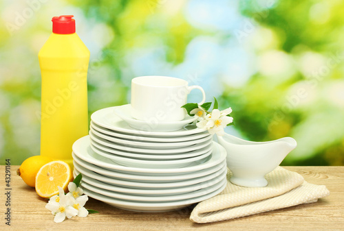Fototapeta Naklejka Na Ścianę i Meble -  empty clean plates and cups with dishwashing liquid, flowers