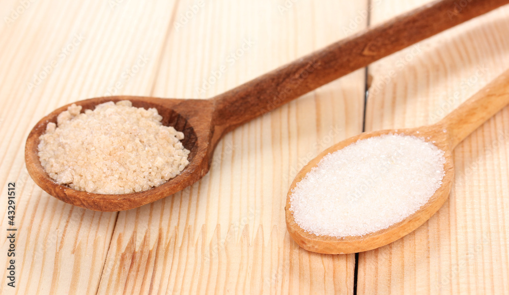 White and brown sugar in spoons on wooden background White and brown sugar in spoons on wooden background