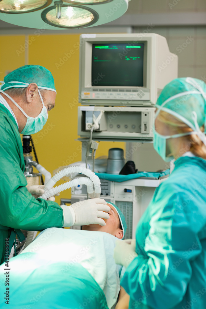 Patient lying on an operating table with two surgeons Patient lying on an operating table with two surgeons