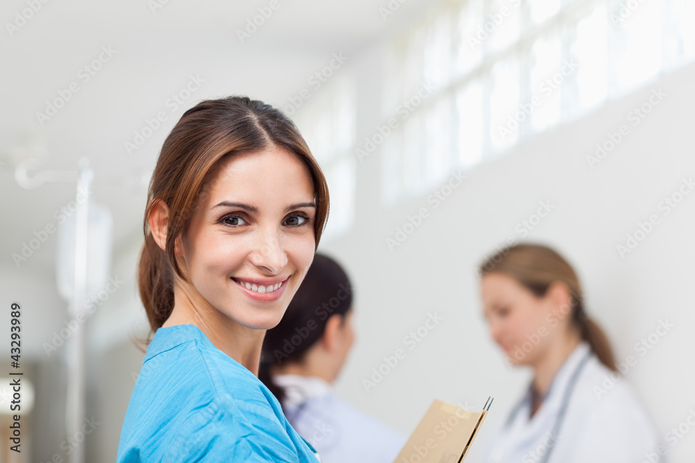 Smiling woman while standing in a hallway with a patient and a Smiling woman while standing in a hallway with a patient and a