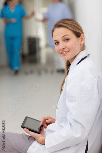 Woman doctor sitting on the floor while holding a tablet
