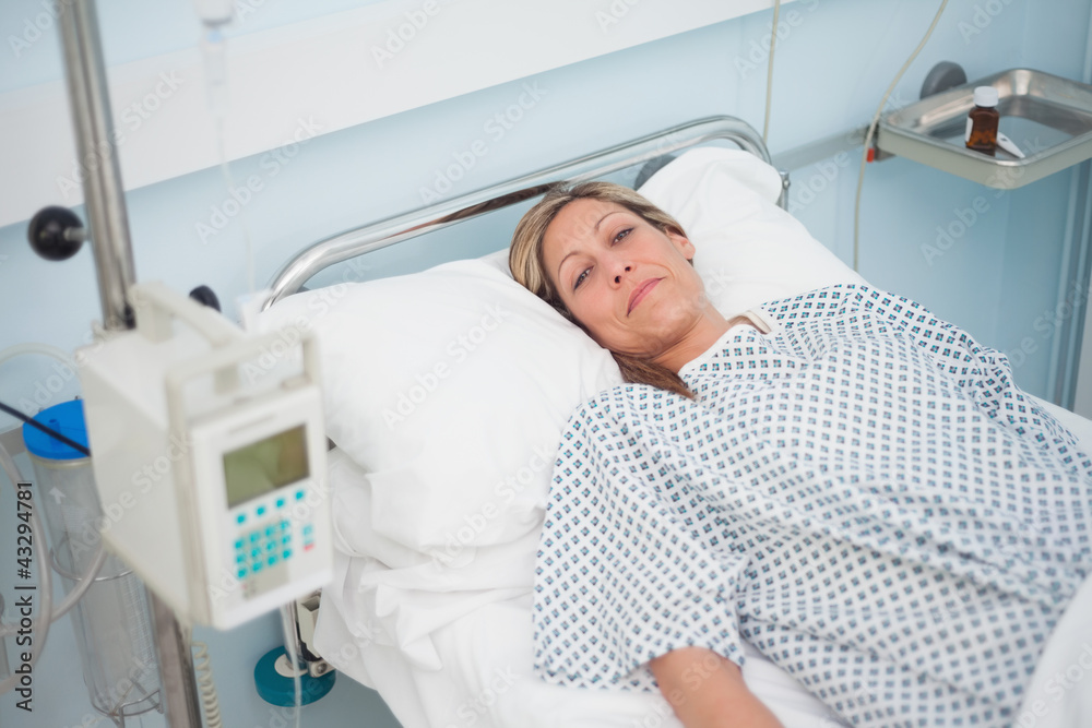 Female patient lying on a bed while looking at camera Female patient lying on a bed while looking at camera