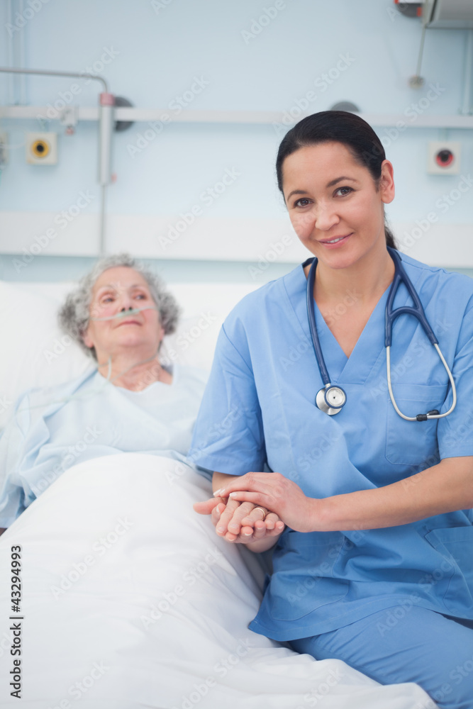 Obraz premium Nurse sitting on the bed next to a patient