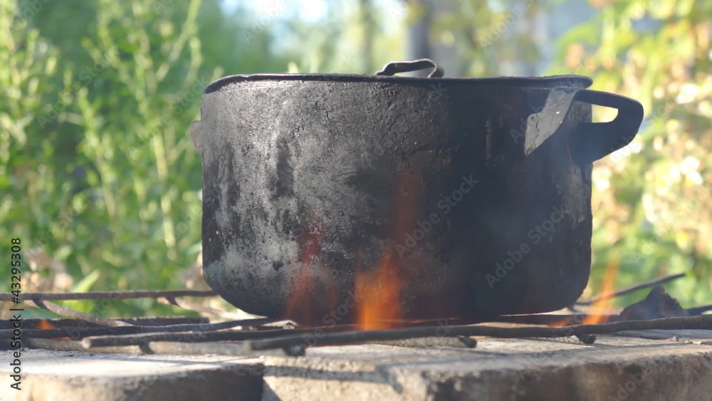 Cooking food in pot outdoors on picnic on open fire Cooking food in pot outdoors on picnic on open fire