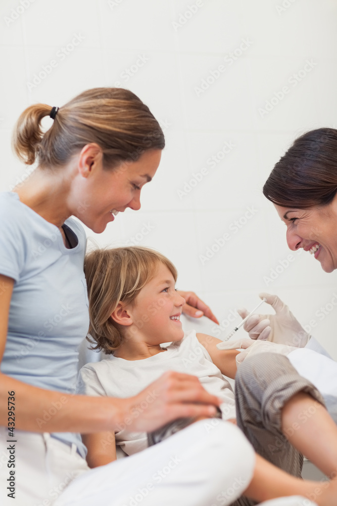 Child sitting on a bed receiving an injection Child sitting on a bed receiving an injection