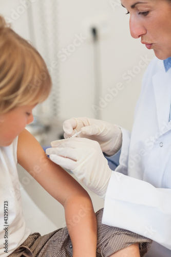 Doctor injecting liquid in a child arm