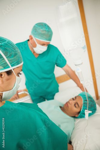 Two surgeons looking at an unconscious  patient