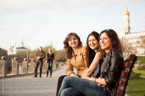 Girls sitting on a bench in city park