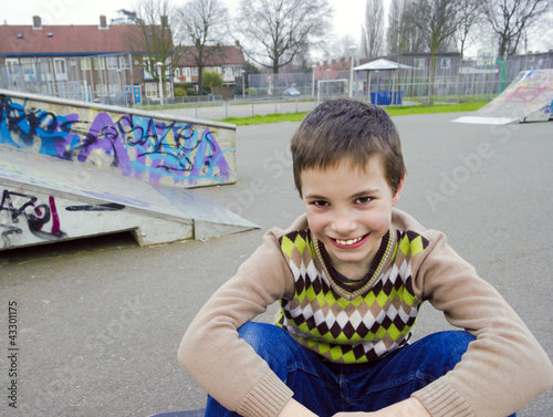 Cute Smiling Boy Sitting In Playground
