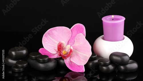 Spa stones with orchid flower and candle isolated on black