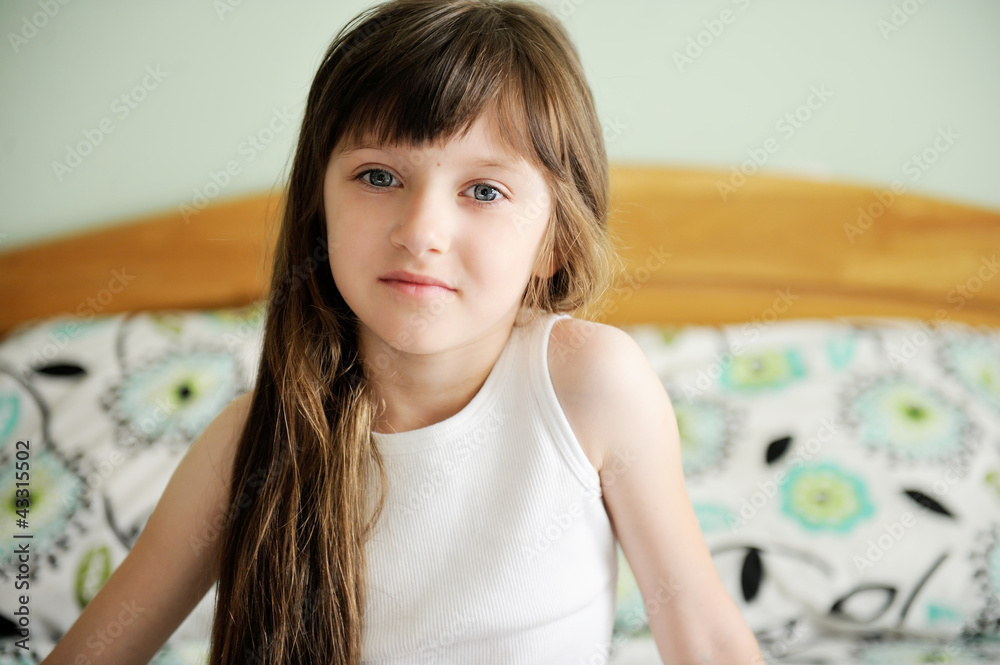 Portrait of awaken little girl sitting in bed