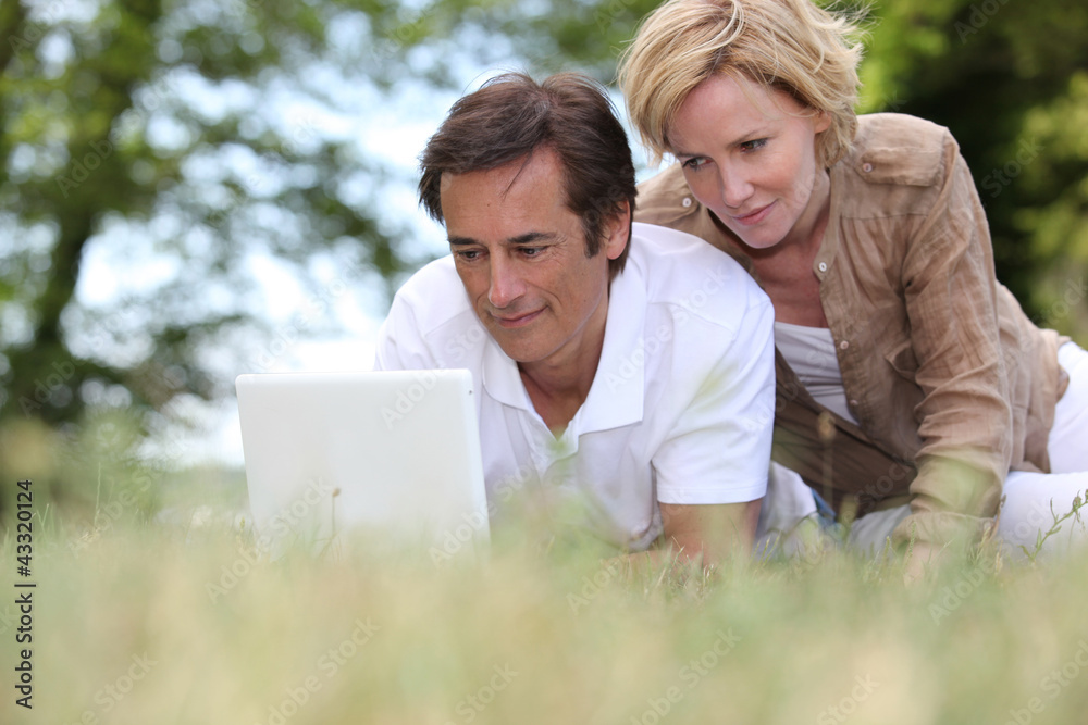 Couple laying in the park with laptop Couple laying in the park with laptop