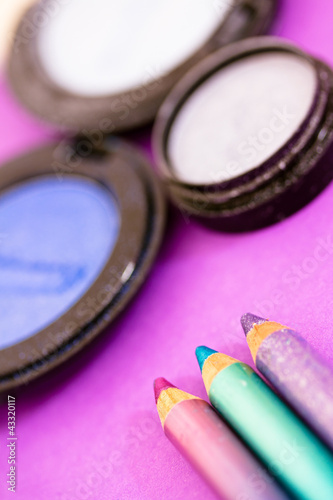 blue eyepencils and eyeshadows on purple background photo