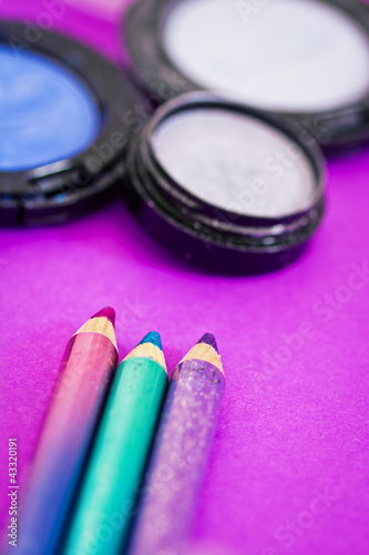 eyepencils and eyeshadows on purple background photo