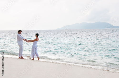 Picture of romantic young couple having a walking on the sea sho