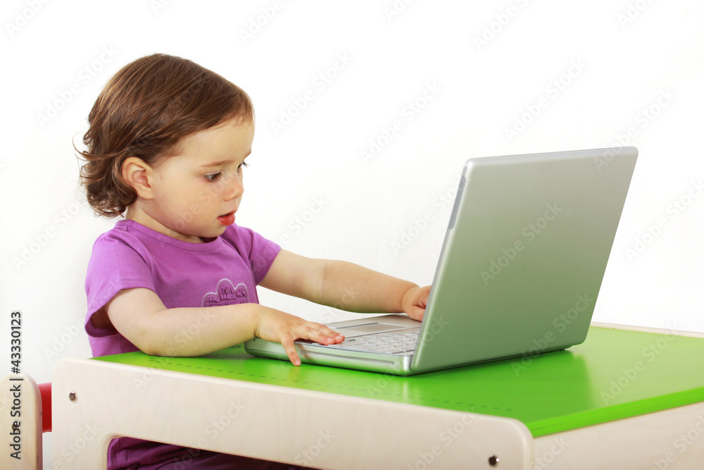 Kind sitzt vor einem Laptop und surft im Internet Kind sitzt vor einem Laptop und surft im Internet